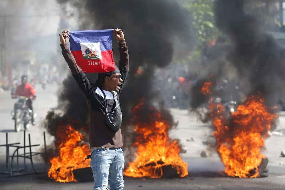 A-demonstrator-holds-up-a-Haitian-flag-during-March-1-protests-in-Port-au-Prince-demanding-the-resign